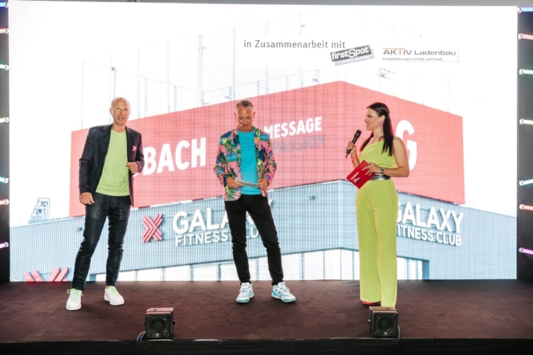 Alexander Leitner, Josef Almer und Moderatorin Conni Kreuter vor der Iconic Screen beim Sommerfest von Goldbach Austria 2024.